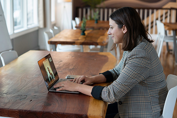 A woman in work attire staring at a laptop talking to a person on video call.
